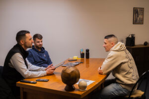 Robin & Paul discute avec un futur adhérent dans le bureau, assis