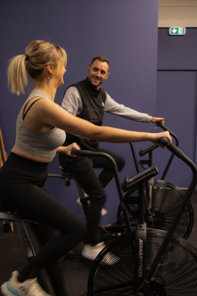 l'adhérente et le coach paul pratiquent en même temps de l'assault bike